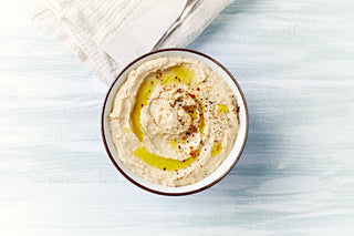 a bowl of hummus on a plain background 