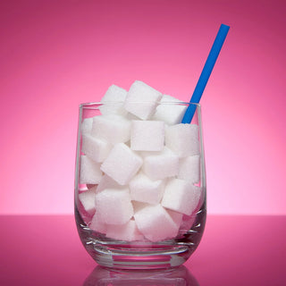 A glass with a blue plastic straw in filled with sugar cubes