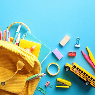 Flay lay image of a backpack with school supplies falling out